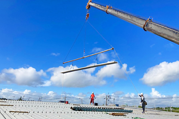 広い屋根の上でクレーンに吊り下げられた折板屋根